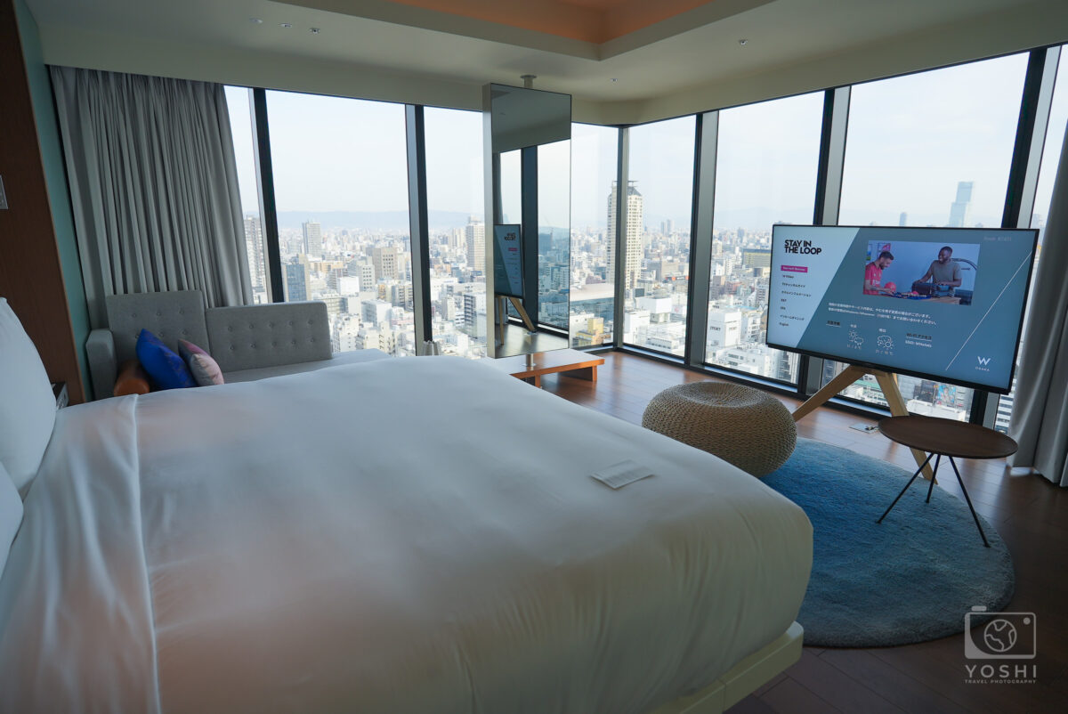 手前にベッド、奥にテレビと窓があるホテルの一室の全景